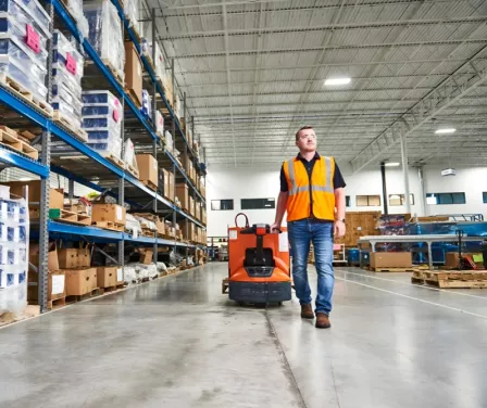Warehouse associate pulling a Toyota electric pallet jack.